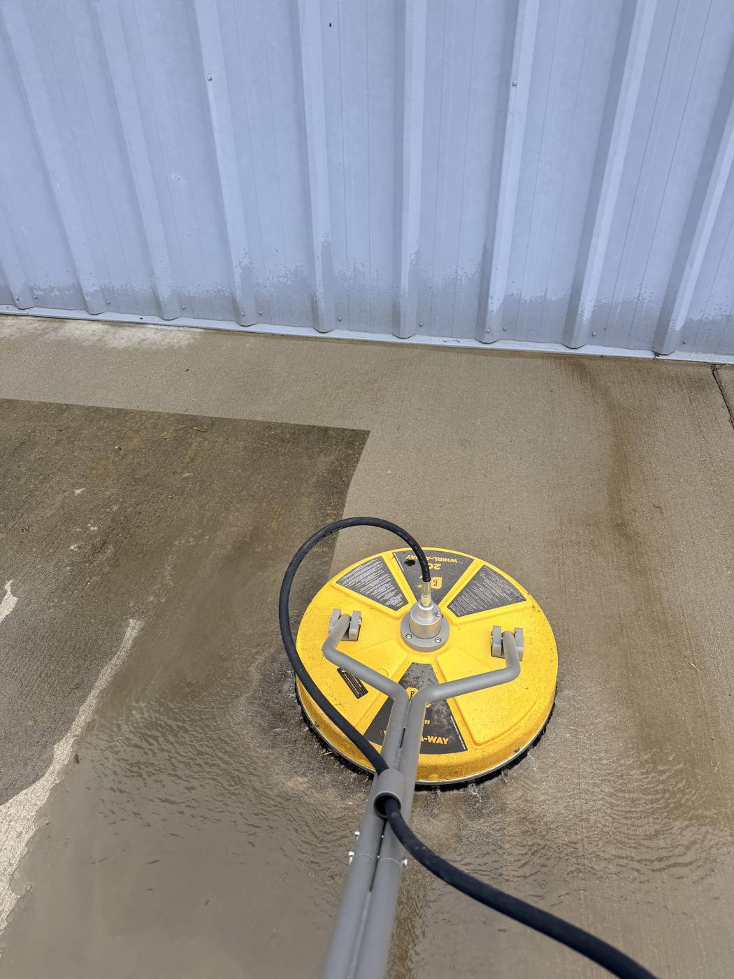 Surface cleaner stripping grime off a concrete pad